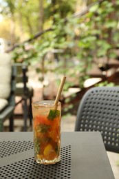 Photo of Glass of tasty refreshing drink and straw on table in outdoor cafe