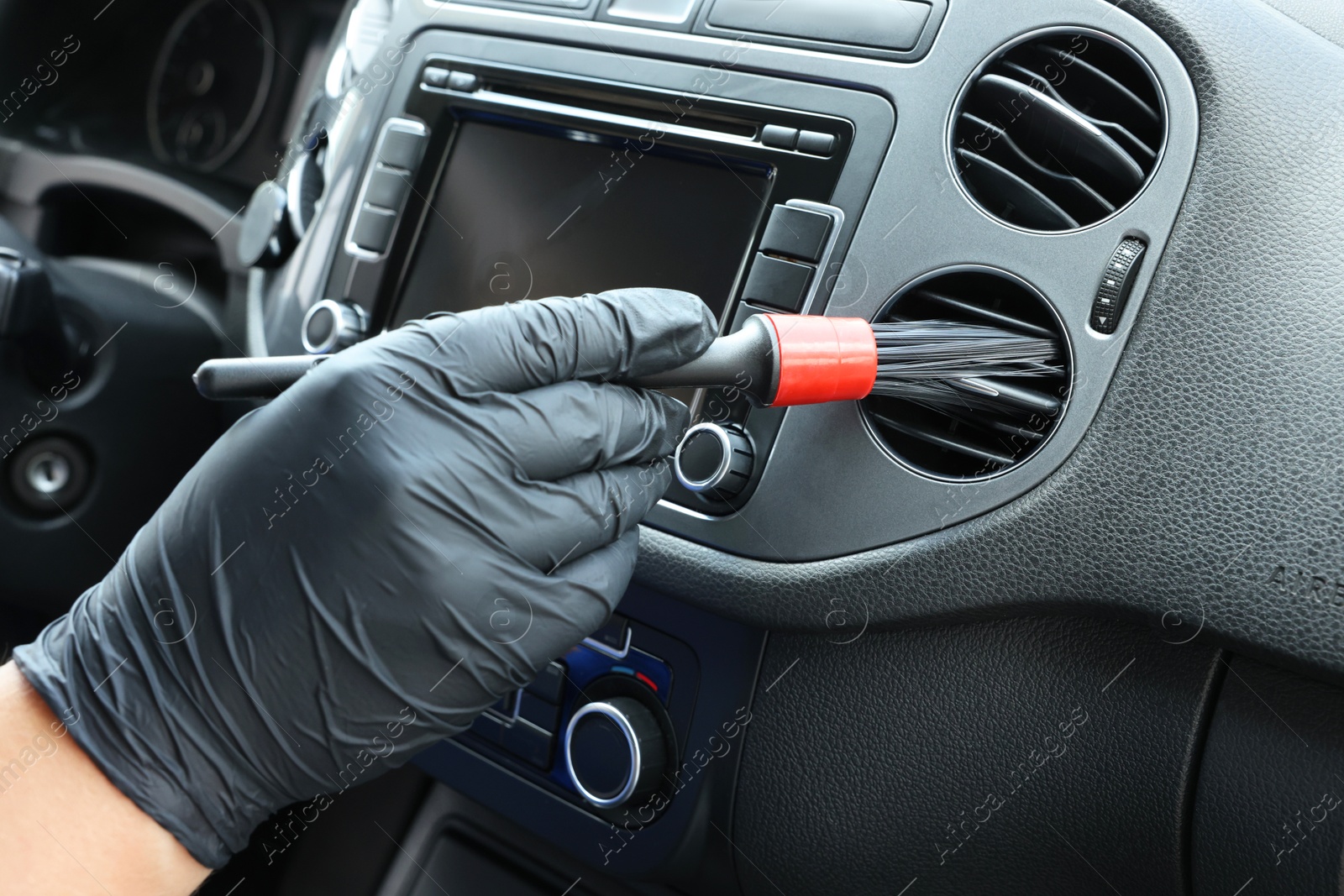 Photo of Man cleaning air vent with brush in car, closeup