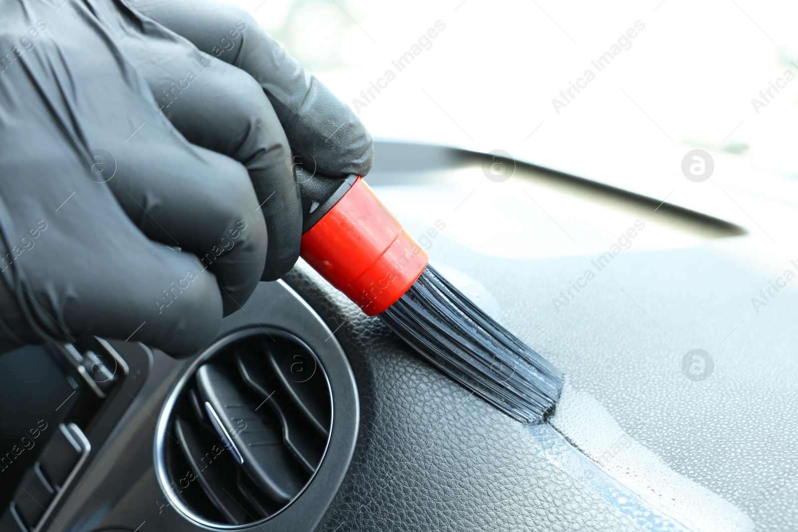 Photo of Man cleaning car interior with brush, closeup