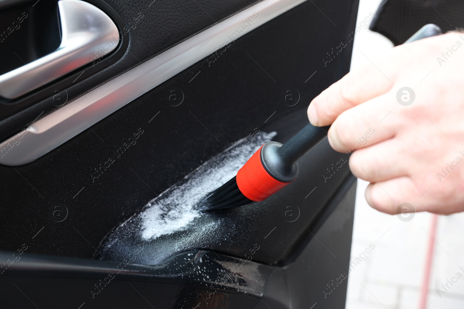 Photo of Man cleaning car door with brush, closeup