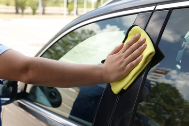 Man wiping car window with yellow rag, closeup