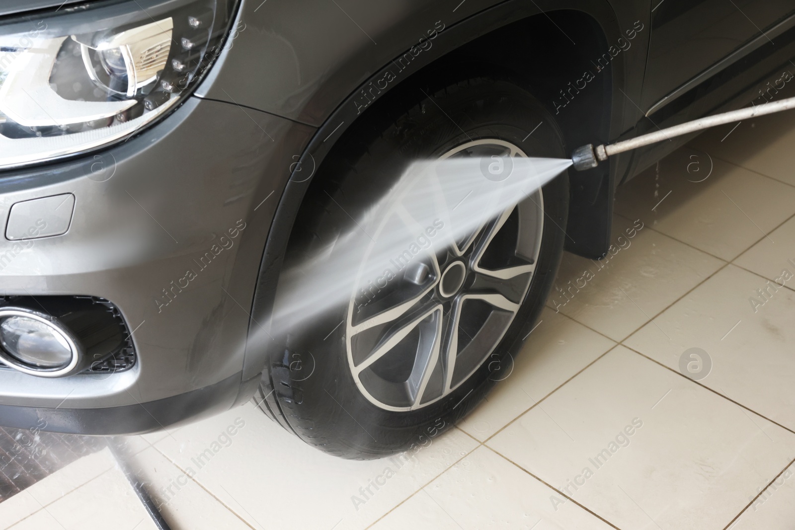 Photo of Washing auto with high pressure water jet at car wash, closeup