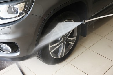 Washing auto with high pressure water jet at car wash, closeup