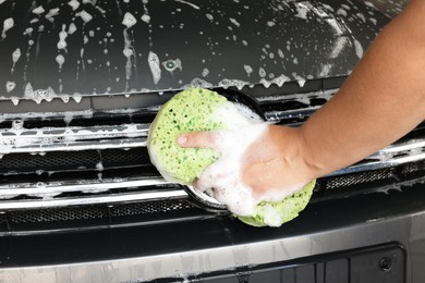 Photo of Man washing car hood with sponge indoors, closeup