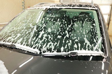 Auto covered with cleaning foam at car wash, closeup