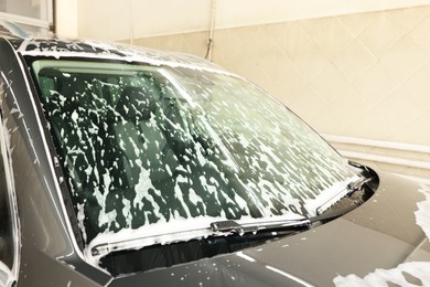 Auto covered with cleaning foam at car wash, closeup