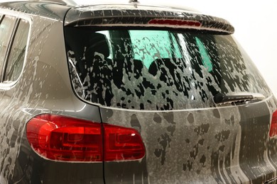 Auto covered with cleaning foam at car wash, closeup