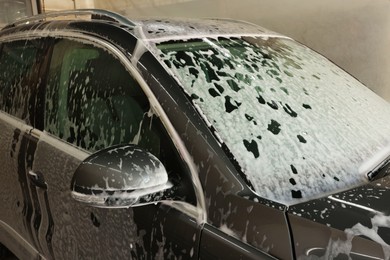 Auto covered with cleaning foam at car wash, closeup