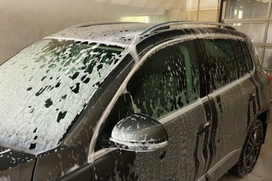 Photo of Auto covered with cleaning foam at car wash, closeup