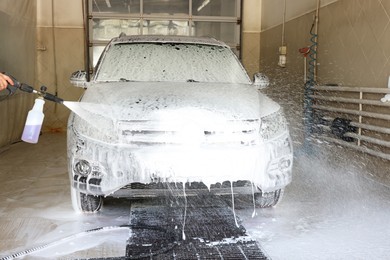 Man washing auto with high pressure water jet at car wash, closeup