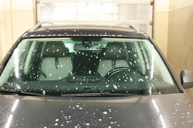 Auto covered with cleaning foam at car wash, closeup