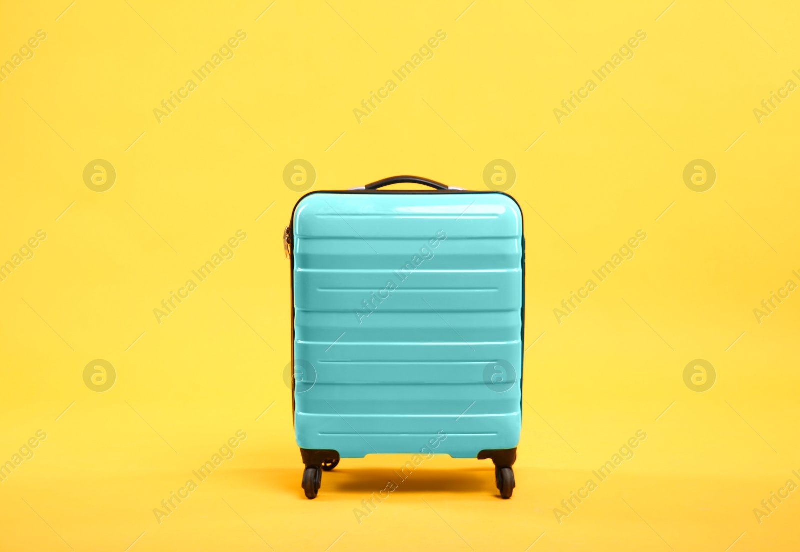 Photo of One new turquoise suitcase on yellow background