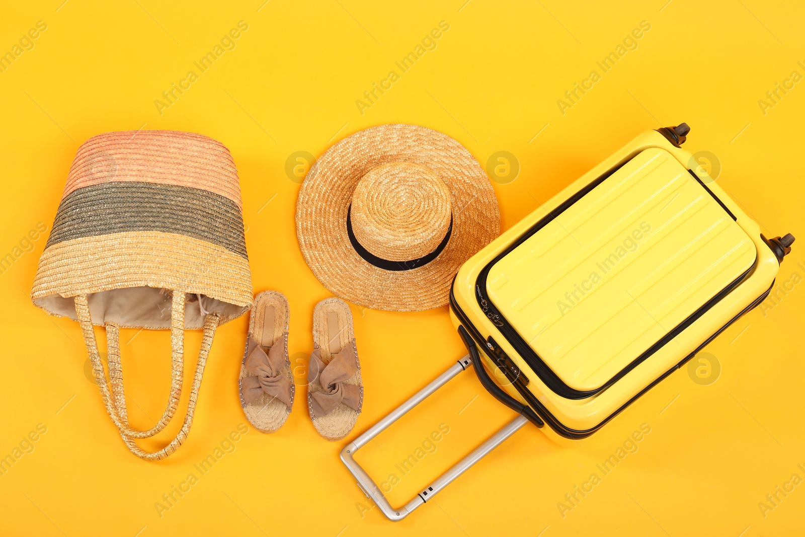 Photo of Suitcase with wicker hat, bag and shoes on yellow background, flat lay