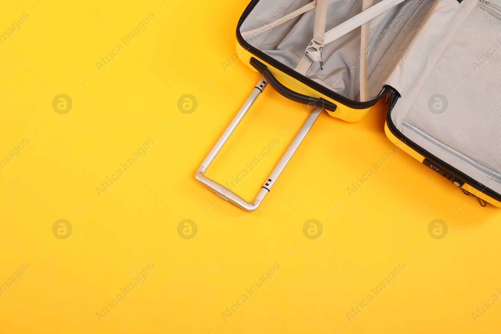 Photo of Open empty suitcase on yellow background, top view. Space for text