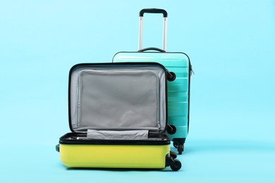 Two bright suitcases on light blue background