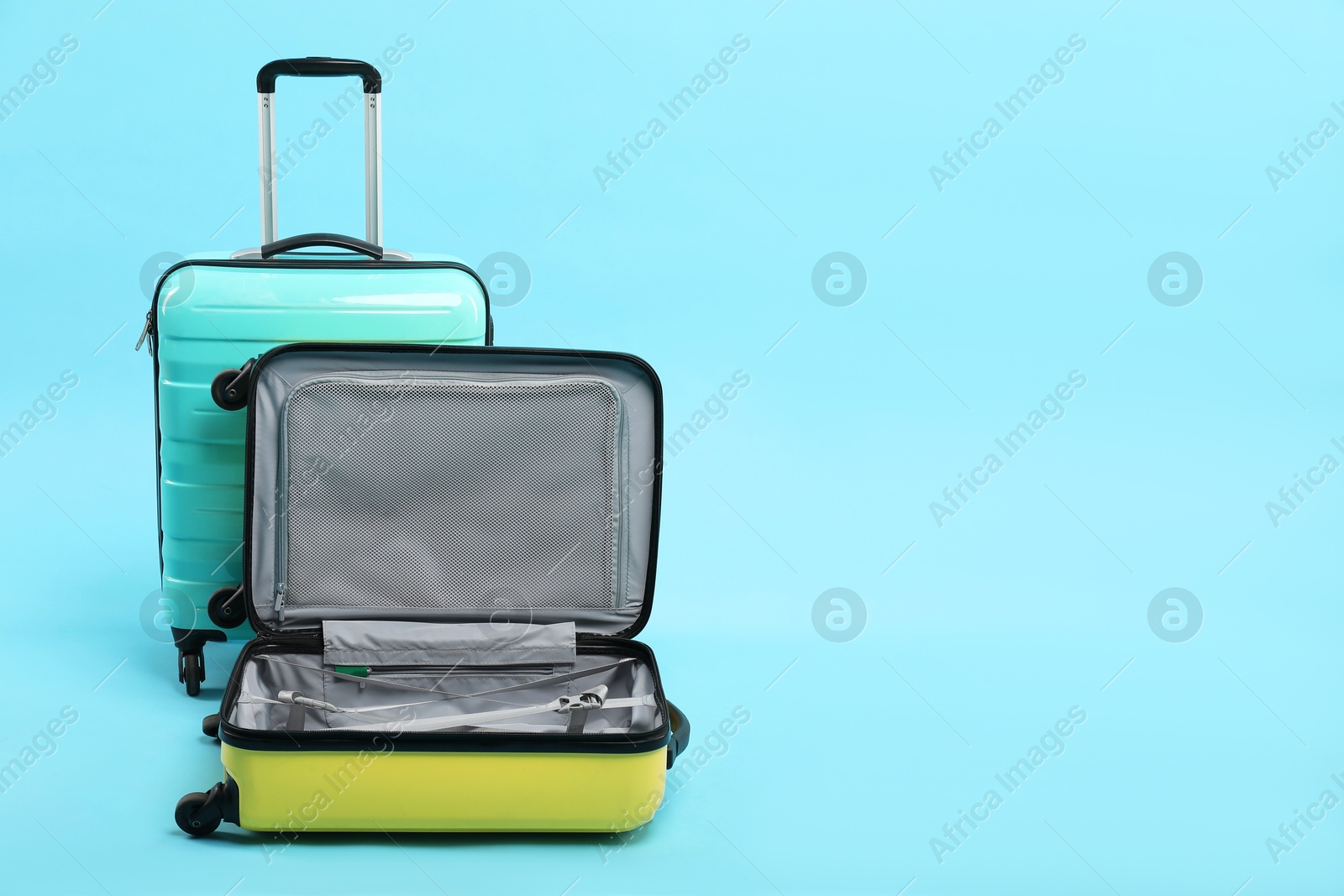 Photo of Two bright suitcases on light blue background, space for text