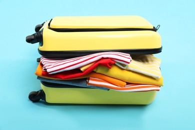 Photo of One suitcase with clothes on light blue background