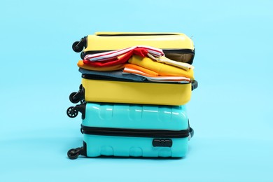 Photo of Two suitcases with clothes on light blue background