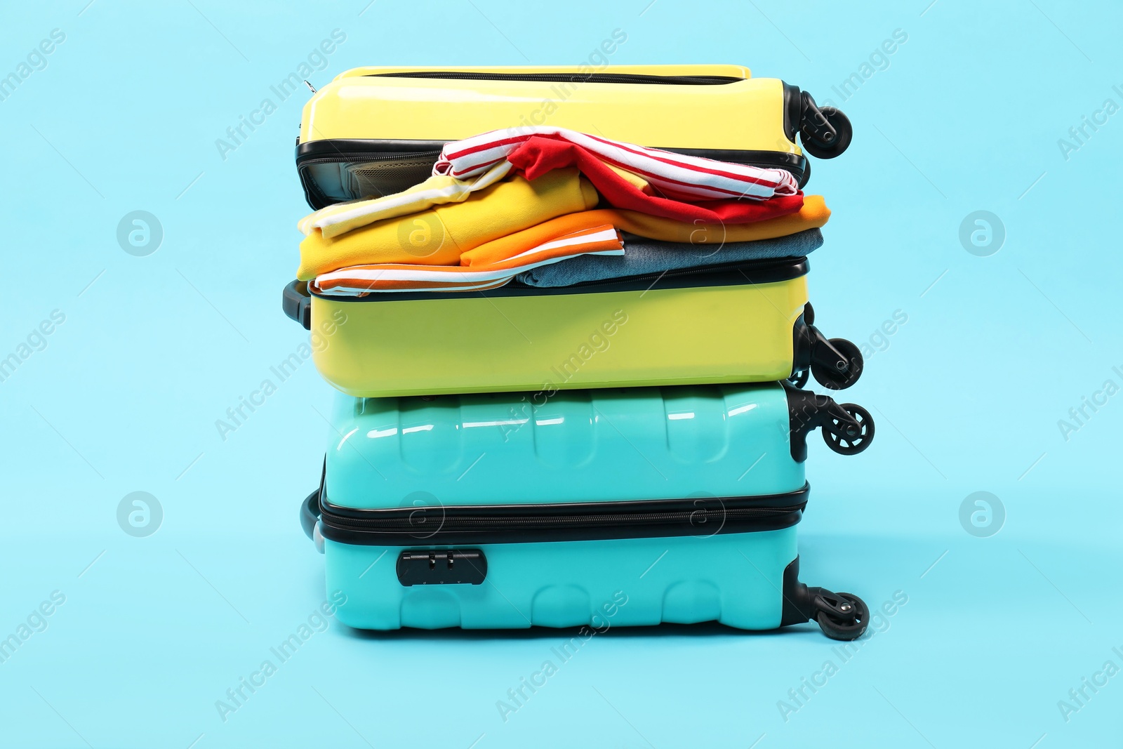 Photo of Two suitcases with clothes on light blue background