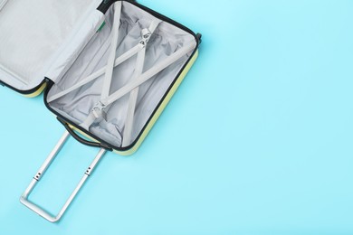 Photo of Open empty suitcase on light blue background, top view. Space for text