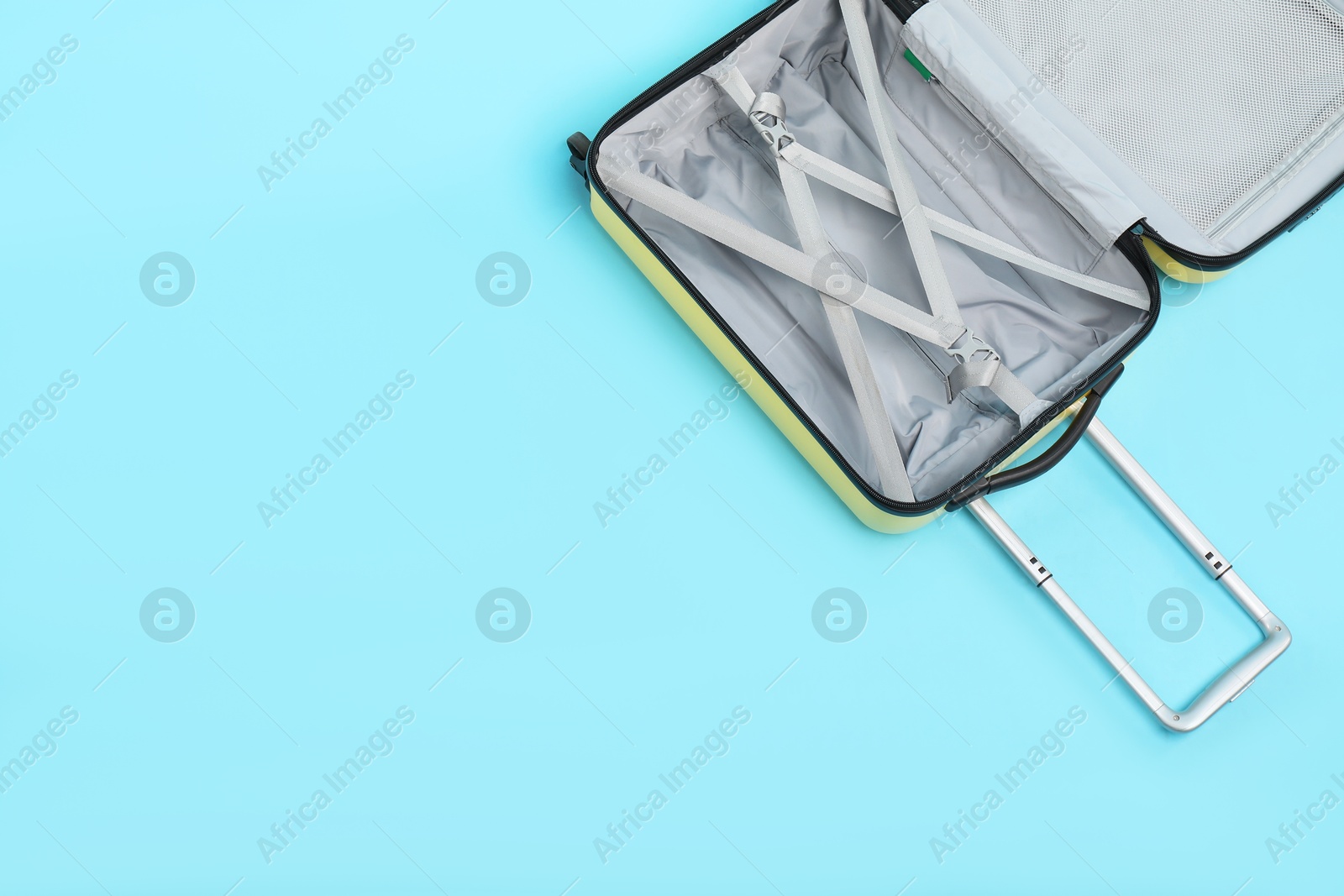 Photo of Open empty suitcase on light blue background, top view. Space for text