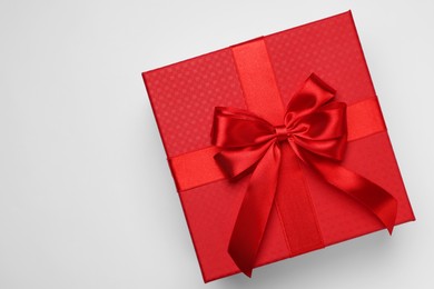 Photo of Gift box with bow on light grey background, top view. Space for text