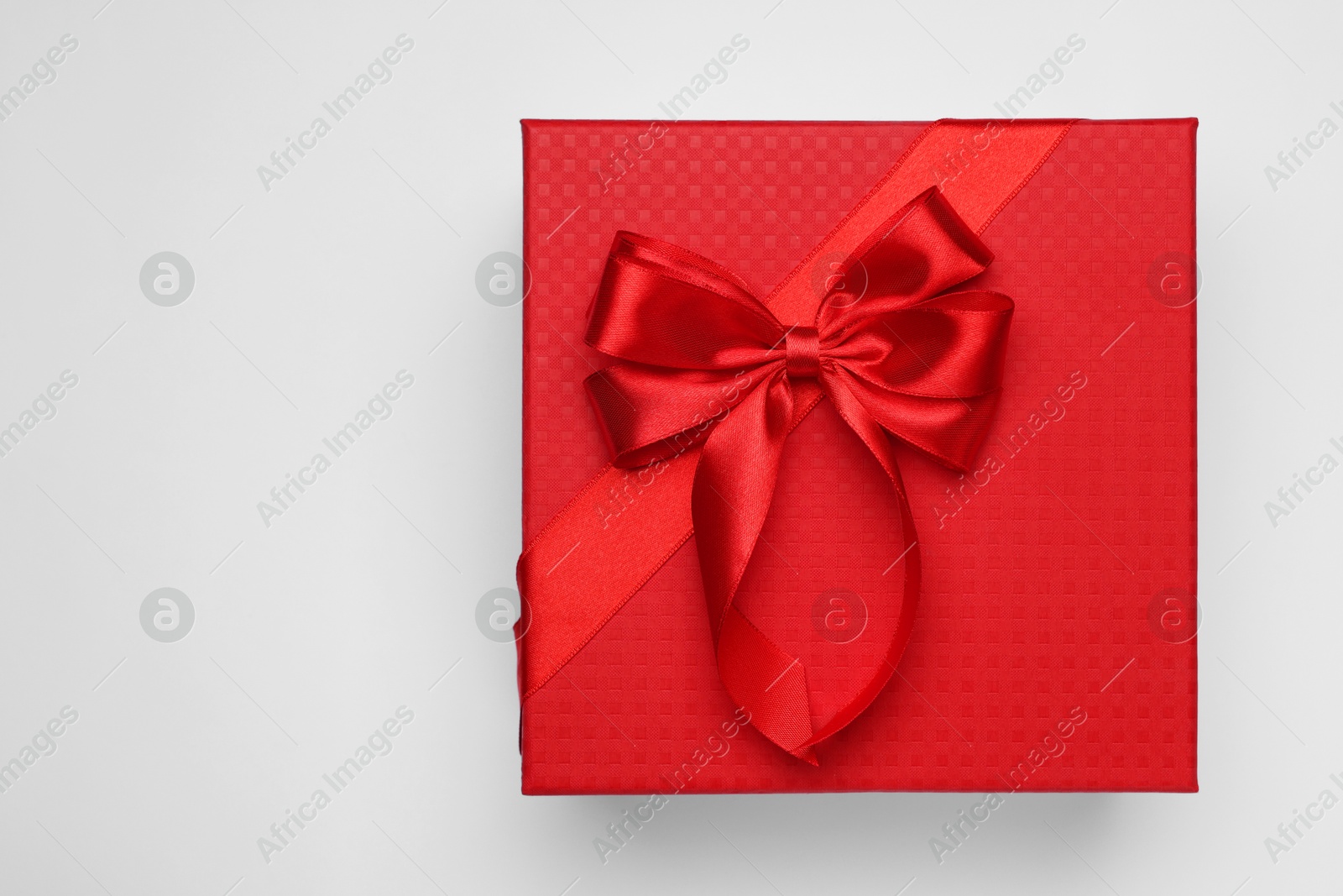 Photo of Gift box with bow on light grey background, top view. Space for text