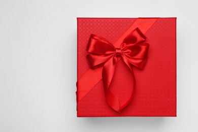 Photo of Gift box with bow on light grey background, top view. Space for text