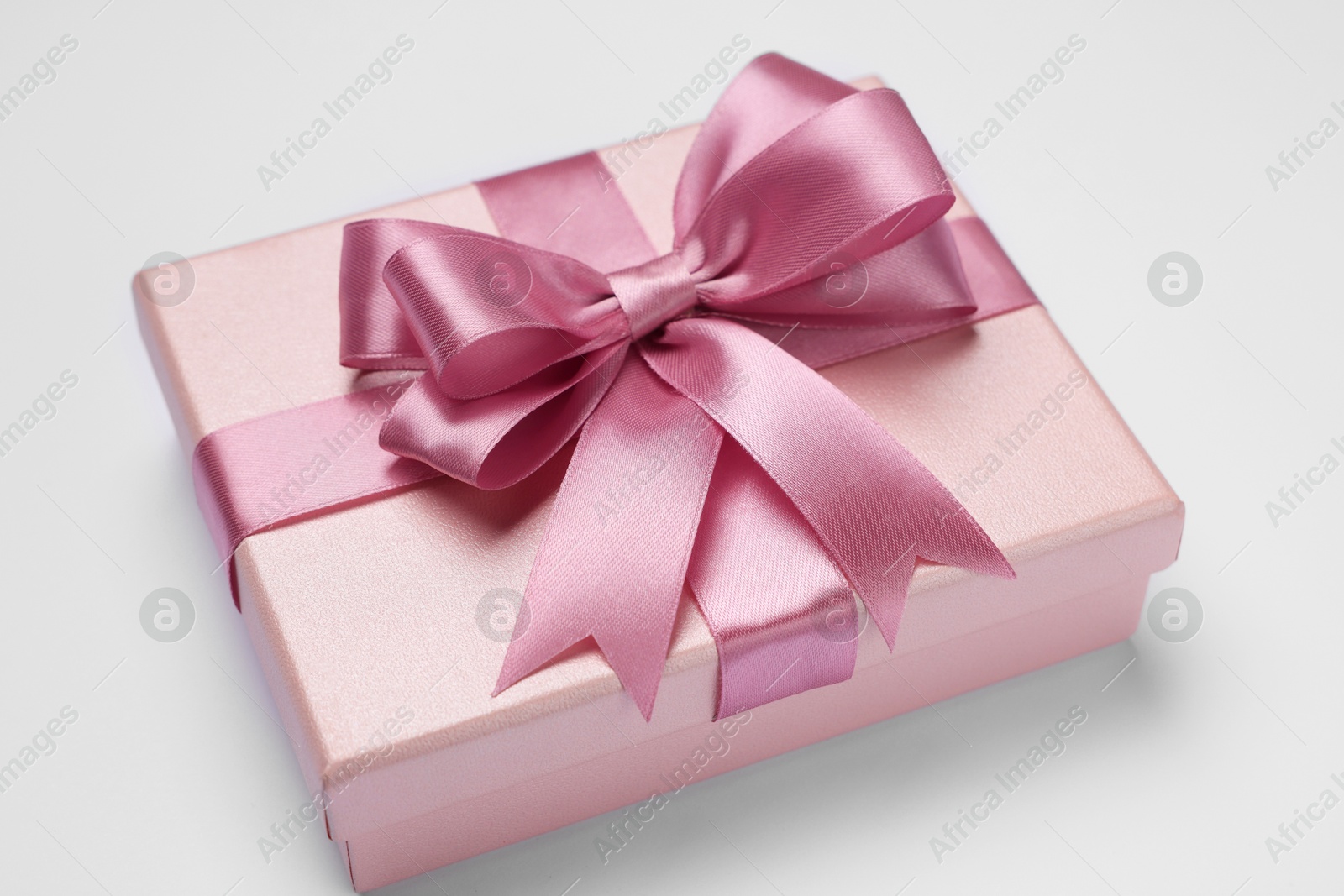 Photo of Gift box with pink bow on light grey background, closeup