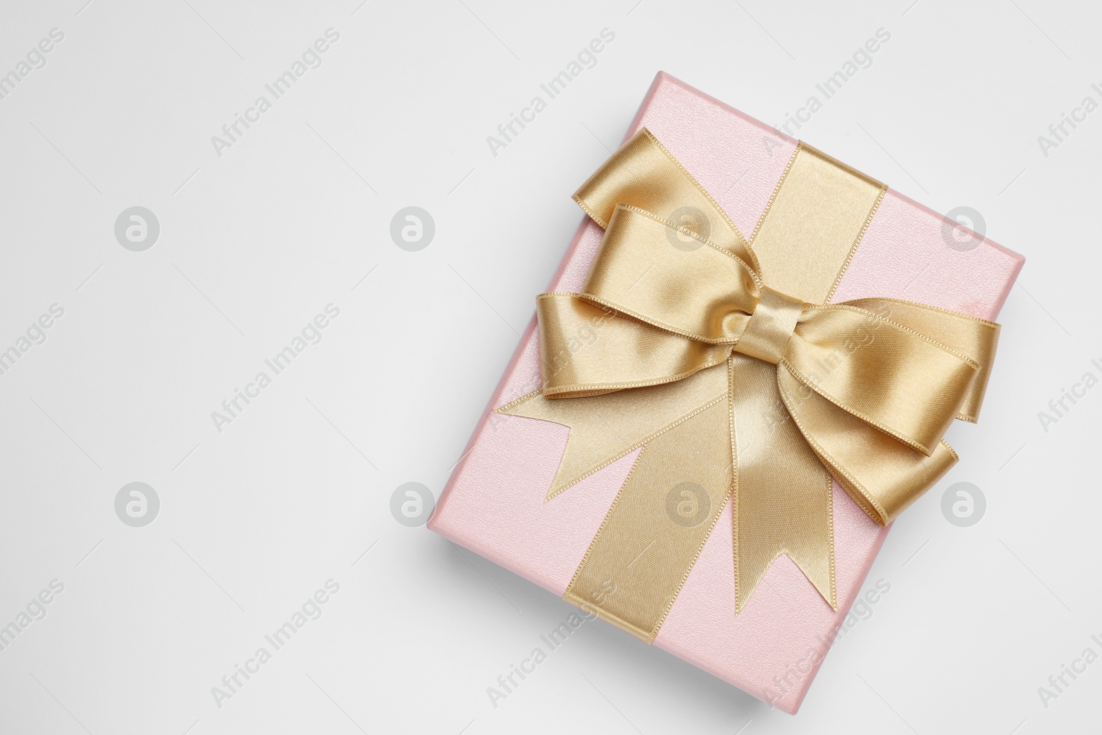 Photo of Gift box with golden bow on light grey background, top view. Space for text