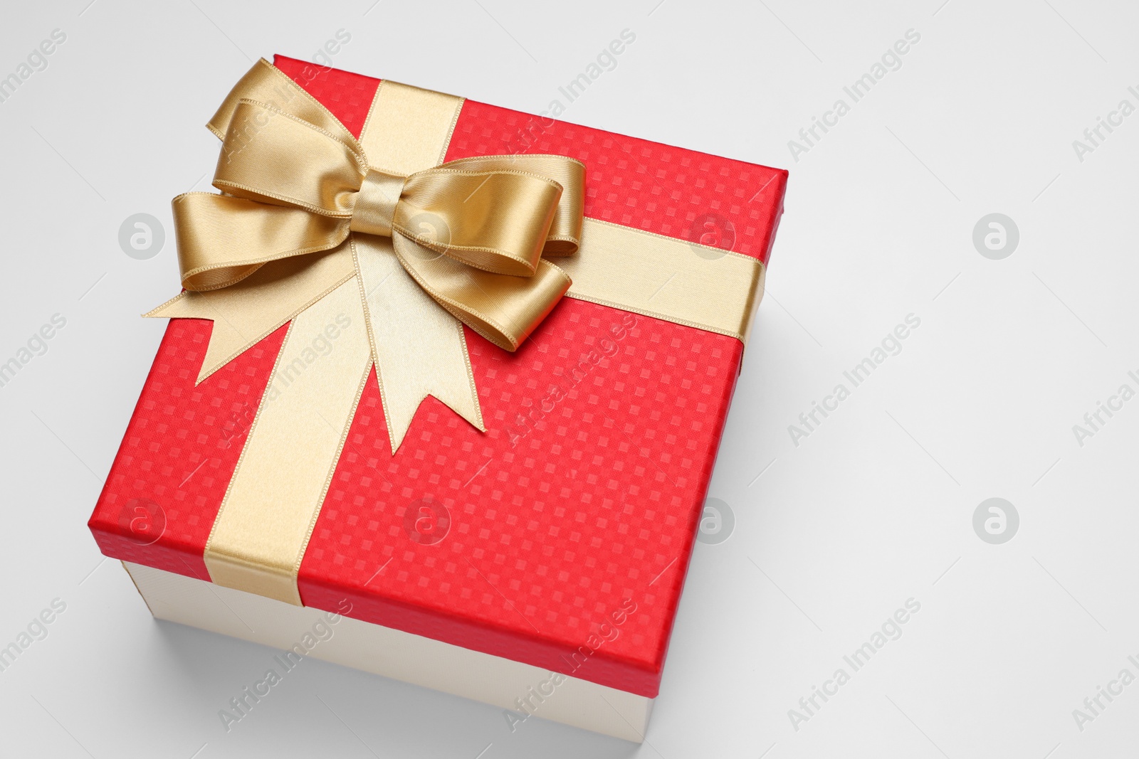 Photo of Gift box with golden bow on light grey background, above view. Space for text