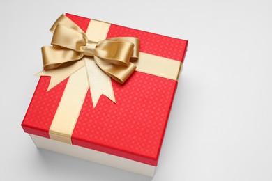 Photo of Gift box with golden bow on light grey background, above view. Space for text