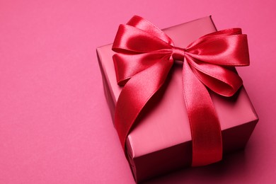 Photo of Gift box with bow on pink background. Space for text