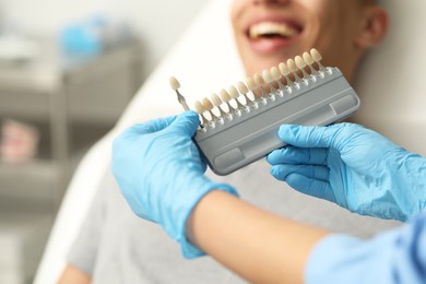 Photo of Doctor checking young man's teeth color in clinic, closeup. Dental veneers