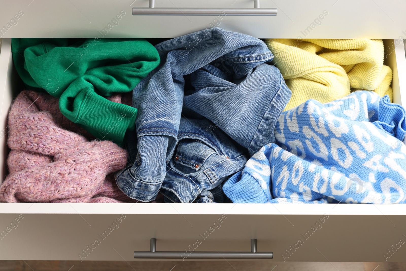 Photo of Cluttered chest of drawers indoors, closeup. Clothes in mess