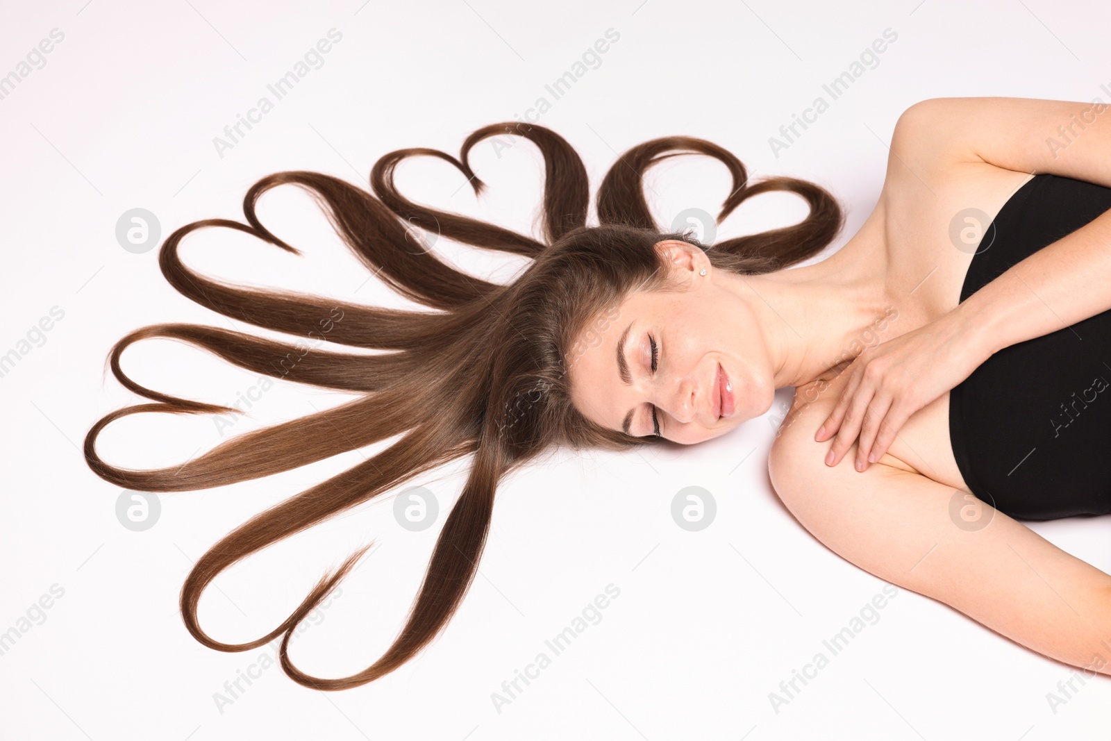 Photo of Beautiful young woman with hair in shape of hearts on white background