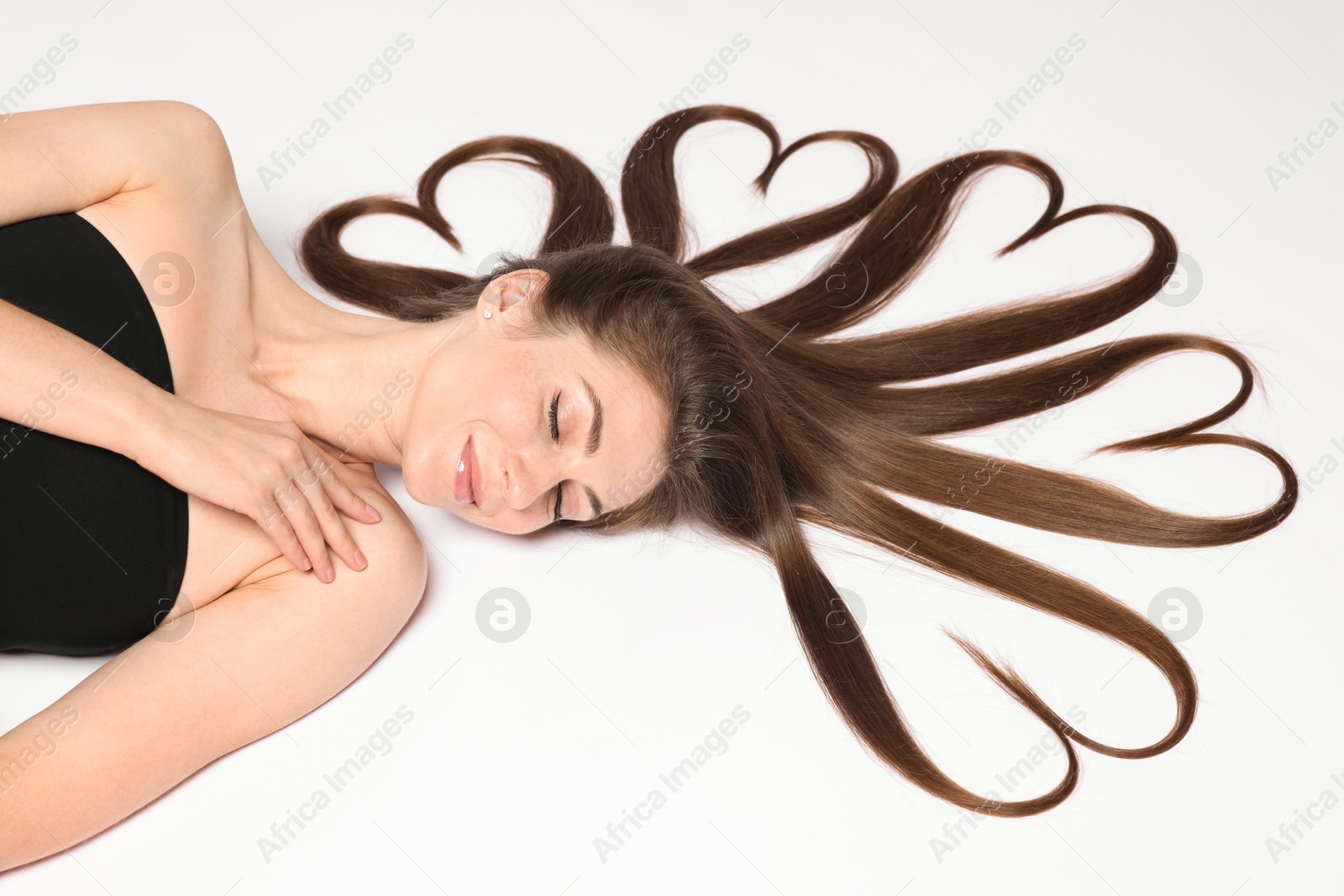 Photo of Beautiful young woman with hair in shape of hearts on white background