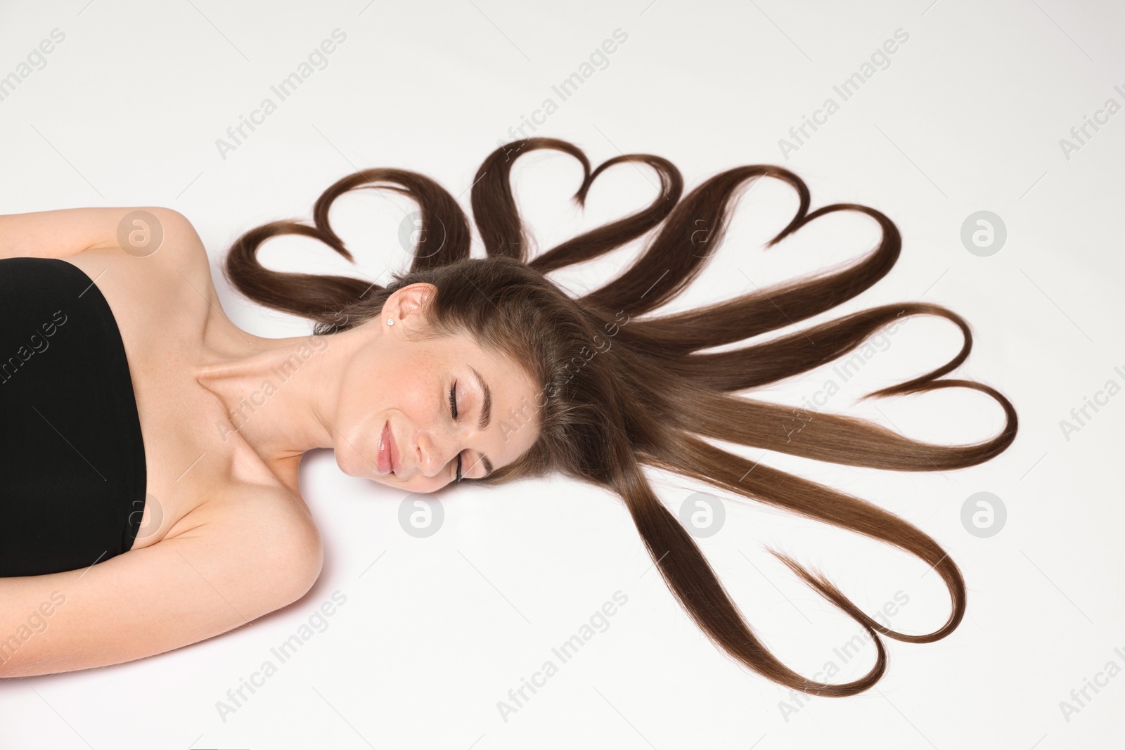 Photo of Beautiful young woman with hair in shape of hearts on white background