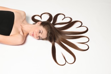 Photo of Beautiful young woman with hair in shape of hearts on white background