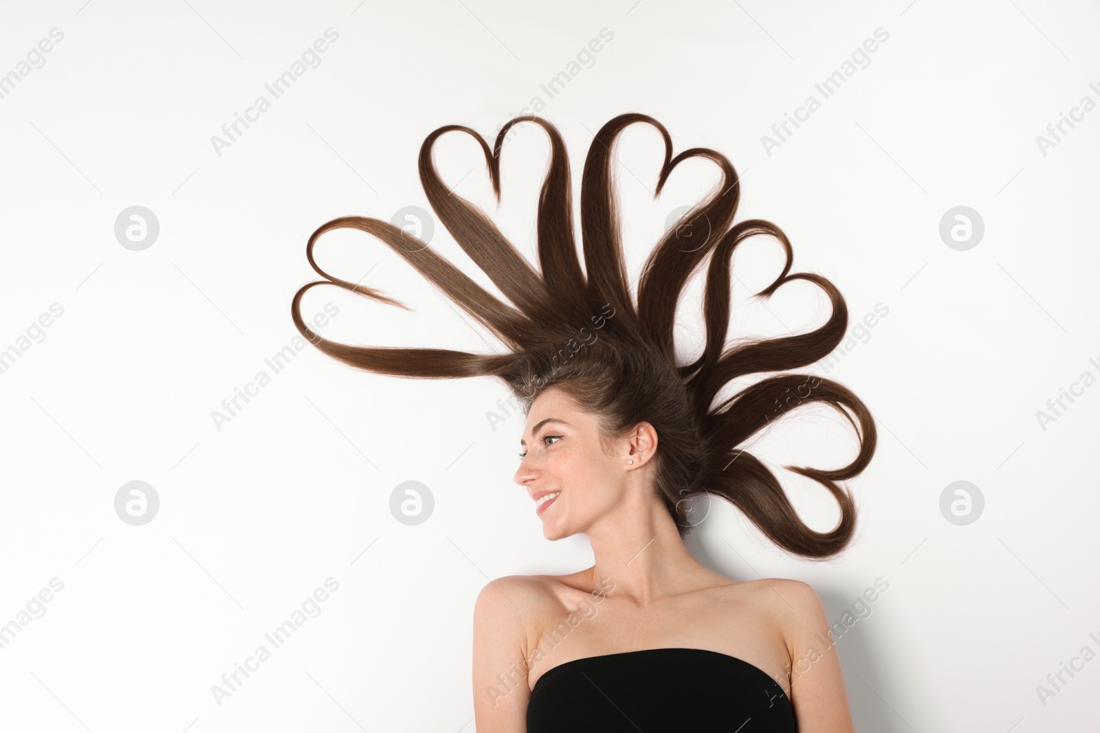 Photo of Beautiful young woman with hair in shape of hearts on white background, top view