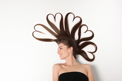 Photo of Beautiful young woman with hair in shape of hearts on white background, top view