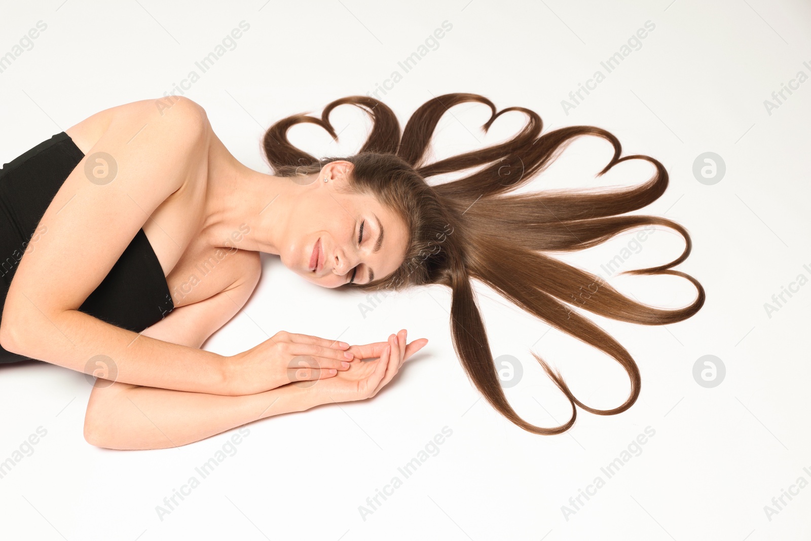 Photo of Beautiful young woman with hair in shape of hearts on white background