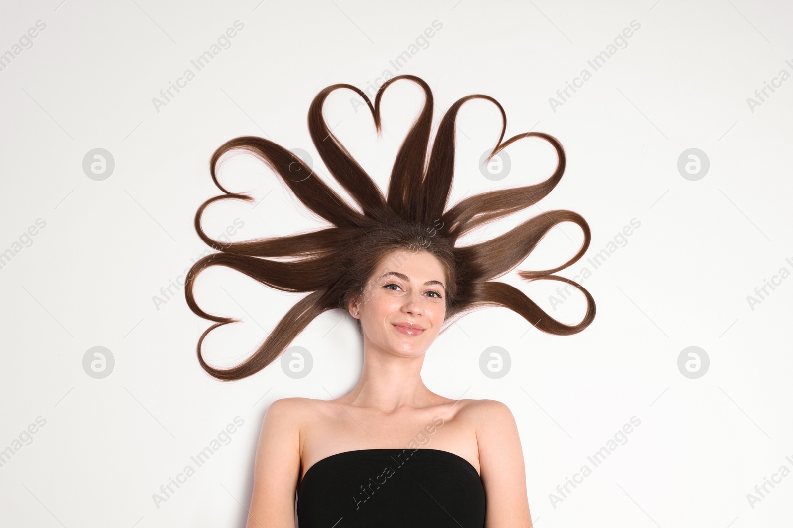 Photo of Beautiful young woman with hair in shape of hearts on white background, top view