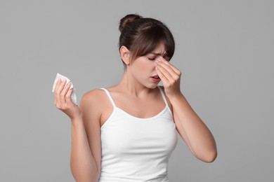 Photo of Woman with napkin suffering from sinusitis on grey background