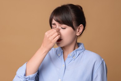 Woman suffering from sinusitis on beige background