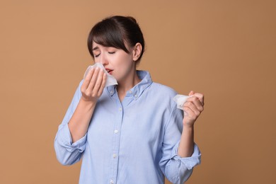 Woman with napkin suffering from sinusitis on beige background