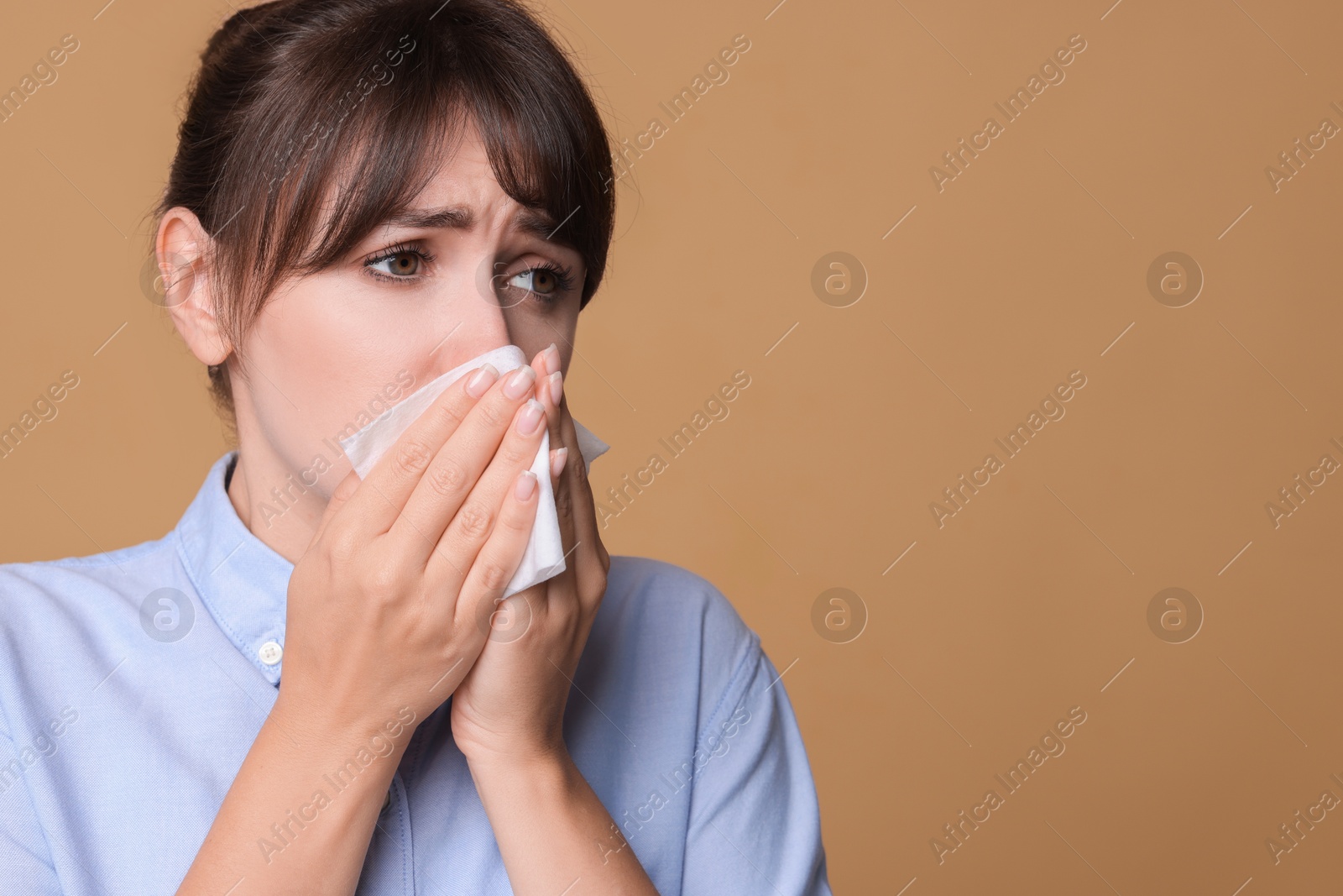 Photo of Woman with napkin suffering from sinusitis on beige background. Space for text