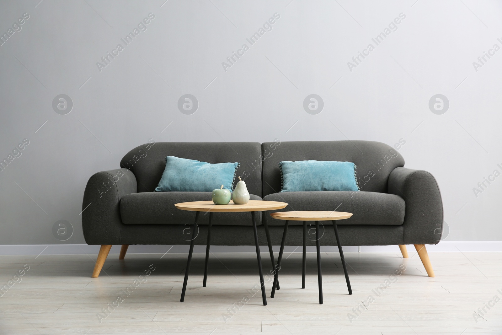 Photo of Comfortable sofa and tables near grey wall in room