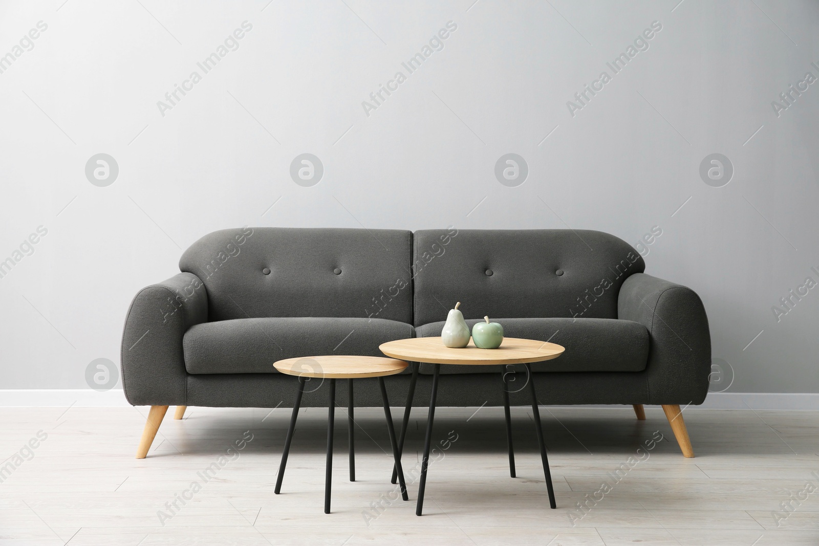 Photo of Comfortable sofa and tables near grey wall in room