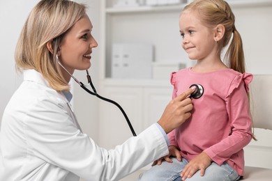 Photo of Doctor examining little girl with stethoscope in hospital